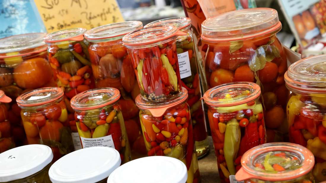 Pomodori e peperoni sottaceto in barattoli di vetro.