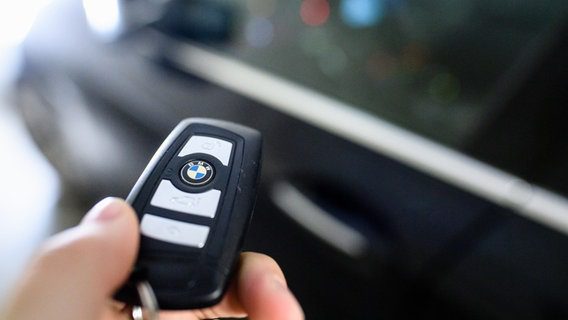 Un uomo tiene in mano la chiave di un'auto BMW.  © Matthias Balk/DPA 