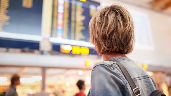 Donna che guarda un display degli orari di partenza all'aeroporto © colorbox Foto:-
